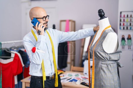 Téléchargez les photos : Young bald man tailor talking on smartphone at tailor shop - en image libre de droit