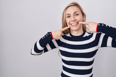 Téléchargez les photos : Jeune femme caucasienne portant un pull marine décontracté souriant et joyeux montrant et pointant du doigt les dents et la bouche. concept de santé dentaire. - en image libre de droit