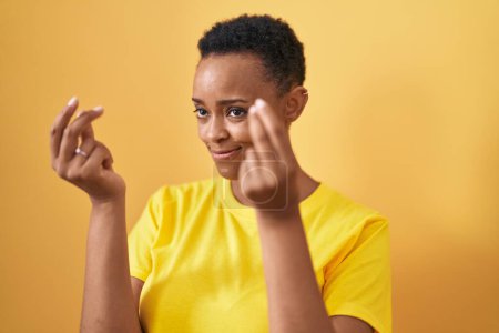 Photo for African american woman smiling confident doing spend money gesture over isolated yellow background - Royalty Free Image