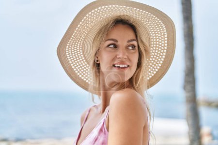 Téléchargez les photos : Young blonde woman tourist smiling confident standing at seaside - en image libre de droit