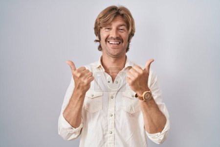 Téléchargez les photos : Homme du moyen âge debout sur le signe isolé de succès de fond faisant geste positif avec la main, pouces levés souriant et heureux. expression joyeuse et geste gagnant. - en image libre de droit