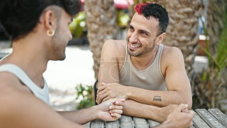 Photo for Two men couple sitting on table speaking at coffee shop terrace - Royalty Free Image