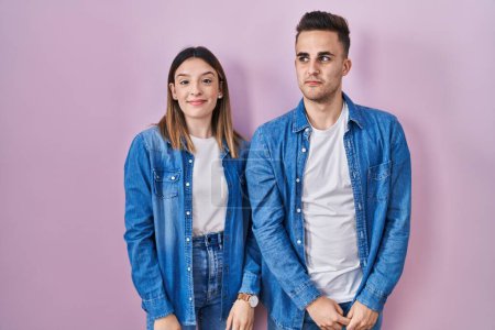 Téléchargez les photos : Young hispanic couple standing over pink background smiling looking to the side and staring away thinking. - en image libre de droit
