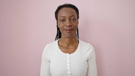 Téléchargez les photos : Femme afro-américaine souriante confiante debout sur fond rose isolé - en image libre de droit