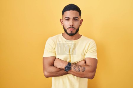 Photo for Young hispanic man standing over yellow background looking sleepy and tired, exhausted for fatigue and hangover, lazy eyes in the morning. - Royalty Free Image