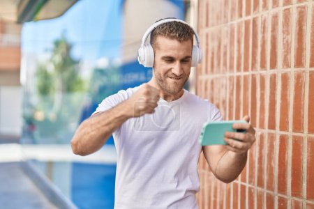 Photo for Young caucasian man smiling confident playing video game at street - Royalty Free Image