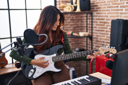 Photo for Young hispanic woman artist playing electrical guitar at music studio - Royalty Free Image