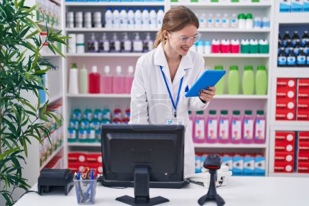 Photo for Young blonde woman pharmacist smiling confident using computer and touchpad at pharmacy - Royalty Free Image
