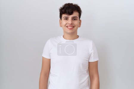 Foto de Joven hombre no binario con camiseta blanca casual con una sonrisa feliz y fresca en la cara. persona afortunada. - Imagen libre de derechos