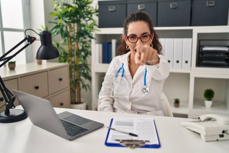 Photo for Young hispanic woman wearing doctor uniform and stethoscope pointing displeased and frustrated to the camera, angry and furious with you - Royalty Free Image
