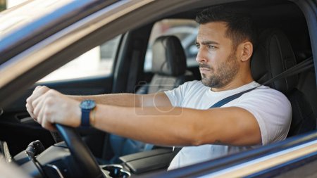 Téléchargez les photos : Jeune homme hispanique conduisant une voiture dans la rue - en image libre de droit