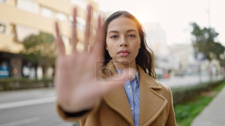 Foto de Joven hermosa mujer hispana haciendo stop gesture con la mano en la calle - Imagen libre de derechos