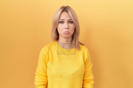 Foto de Mujer caucásica joven con suéter amarillo deprimido y preocupación por la angustia, llorando enojado y asustado. expresión triste. - Imagen libre de derechos
