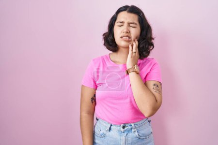 Téléchargez les photos : Jeune femme hispanique debout sur fond rose touchant la bouche avec la main avec une expression douloureuse à cause de maux de dents ou de maladies dentaires sur les dents. dentiste - en image libre de droit