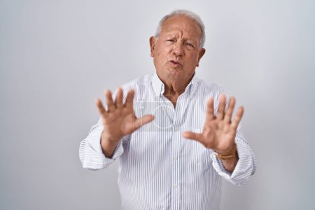 Photo for Senior man with grey hair standing over isolated background moving away hands palms showing refusal and denial with afraid and disgusting expression. stop and forbidden. - Royalty Free Image