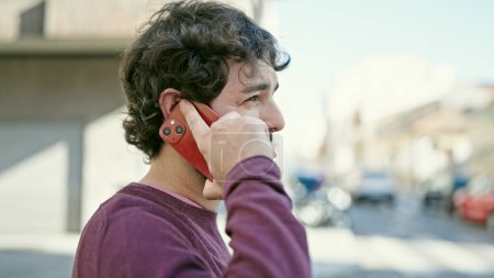 Téléchargez les photos : Young hispanic man talking on smartphone with serious expression at street - en image libre de droit