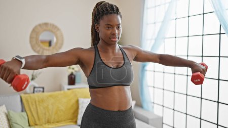 Téléchargez les photos : Femme afro-américaine utilisant haltères formation à la maison - en image libre de droit