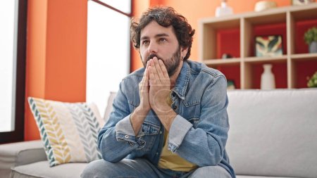Photo for Young hispanic man stressed sitting on sofa at home - Royalty Free Image