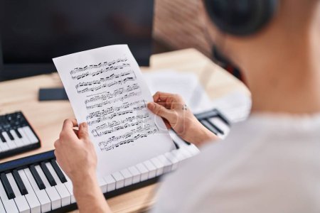Téléchargez les photos : Jeune homme arabe musicien lisant une partition musicale au studio de musique - en image libre de droit