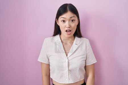 Foto de Mujer joven china de pie sobre fondo rosa miedo y sorprendido con la sorpresa y la expresión asombrada, miedo y cara emocionada. - Imagen libre de derechos