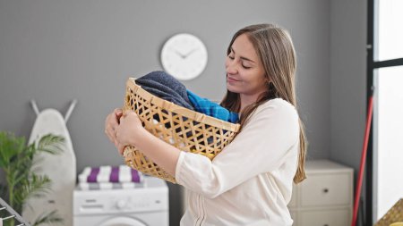 Photo for Young beautiful hispanic woman smiling confident holding wicker basket with clothes at laundry room - Royalty Free Image