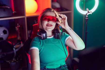 Téléchargez les photos : Jeune rousse femme streamer jouer jeu vidéo en utilisant des lunettes de réalité virtuelle à la salle de jeu - en image libre de droit
