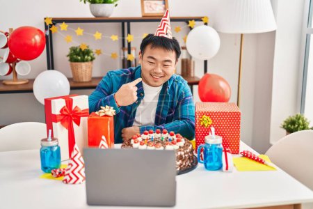 Téléchargez les photos : Jeune homme chinois célébrant anniversaire avec gâteau faire appel vidéo sourire heureux pointant avec la main et le doigt - en image libre de droit