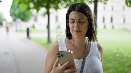 Photo for Young beautiful hispanic woman smiling happy using smartphone at the park in Vienna - Royalty Free Image