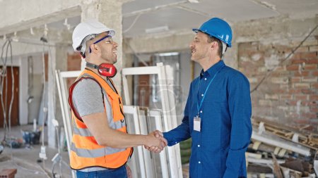 Photo for Two men builder and architect shake hands speaking at construction site - Royalty Free Image