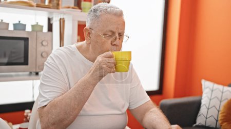 Photo for Middle age grey-haired man drinking coffee sitting on table at dinning room - Royalty Free Image