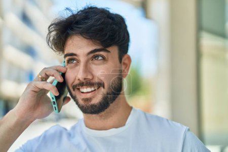 Photo for Young hispanic man smiling confident talking on the smartphone at street - Royalty Free Image