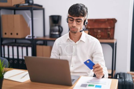 Photo for Young hispanic man working using computer laptop holding credit card depressed and worry for distress, crying angry and afraid. sad expression. - Royalty Free Image