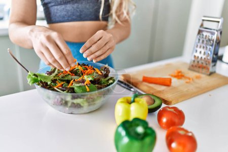 Photo for Young woman pouring carrot on salad at kitchen - Royalty Free Image
