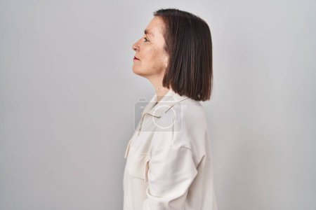 Téléchargez les photos : Middle age hispanic woman standing over isolated background looking to side, relax profile pose with natural face and confident smile. - en image libre de droit