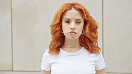 Young redhead woman standing with relaxed expression over isolated white background