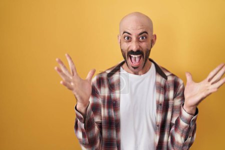 Photo for Hispanic man with beard standing over yellow background celebrating crazy and amazed for success with arms raised and open eyes screaming excited. winner concept - Royalty Free Image