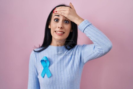 Téléchargez les photos : Hispanic woman wearing blue ribbon stressed and frustrated with hand on head, surprised and angry face - en image libre de droit