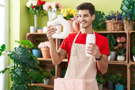 Photo for Young hispanic man florist smiling confident holding plant jars at flower shop - Royalty Free Image