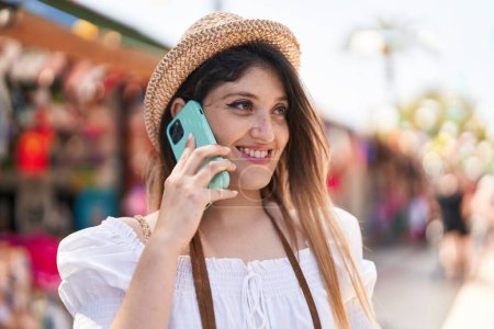 Téléchargez les photos : Jeune femme hispanique touriste souriant confiant parler sur smartphone au marché de la rue - en image libre de droit
