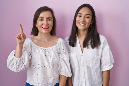 Photo for Hispanic mother and daughter together showing and pointing up with finger number one while smiling confident and happy. - Royalty Free Image