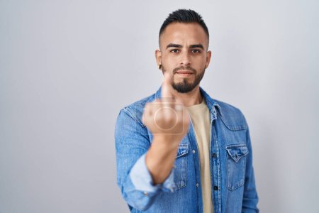 Foto de Young hispanic man standing over isolated background showing middle finger, impolite and rude fuck off expression - Imagen libre de derechos