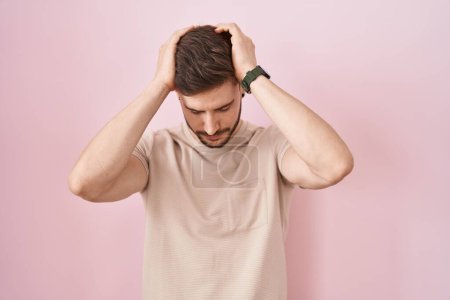 Photo for Hispanic man with beard standing over pink background suffering from headache desperate and stressed because pain and migraine. hands on head. - Royalty Free Image