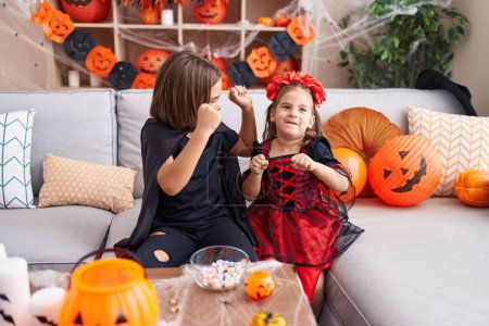 Foto de Adorable chico y chica teniendo fiesta de halloween con la expresión ganadora en casa - Imagen libre de derechos