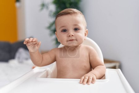 Photo for Adorable caucasian baby sitting on highchair at home - Royalty Free Image