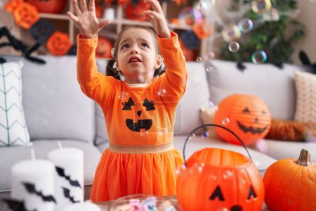 Photo for Adorable hispanic girl having halloween party playing with soap bubbles at home - Royalty Free Image