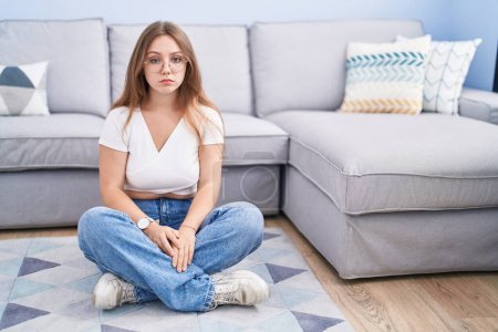 Téléchargez les photos : Jeune femme caucasienne assise par terre au salon déprimée et inquiète pour la détresse, pleurant en colère et effrayée. triste expression. - en image libre de droit
