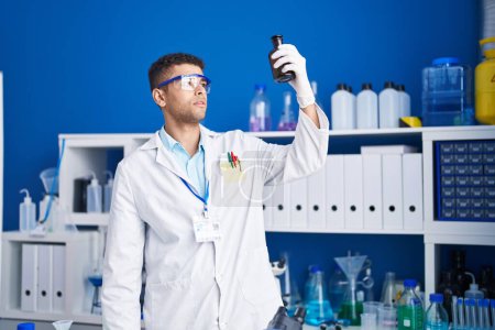Téléchargez les photos : African american man scientist holding bottle at laboratory - en image libre de droit