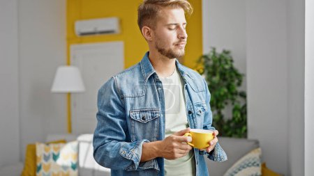 Photo for Young caucasian man drinking coffee standing at home - Royalty Free Image