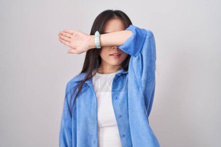 Photo for Young chinese woman standing over white background covering eyes with arm, looking serious and sad. sightless, hiding and rejection concept - Royalty Free Image