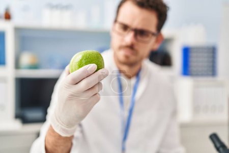 Téléchargez les photos : Jeune homme hispanique scientifique tenant pomme au laboratoire - en image libre de droit
